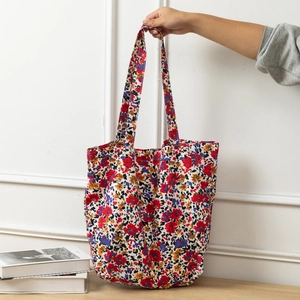Detail of floral canvas tote bag showing red and purple flower pattern with long handle