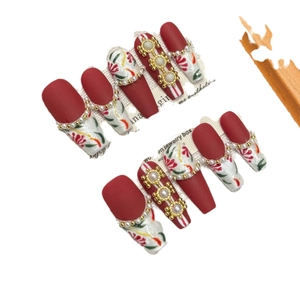 Red and white handmade press-on nails with floral patterns and pearl ornaments