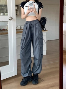 Detail view of dark grey cargo pants with multi-pocket design and drawstring waist on model