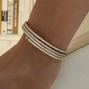 Close-up of a four-layer gold-plated tennis bracelet set with clear cubic zirconia crystals