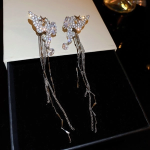 Close-up of sparkling silver wing earrings with long tassels and inlaid zircons