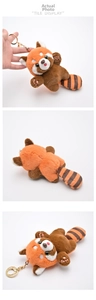 Macro shot of cute red panda plush keychain with orange faux fur and golden metal ring