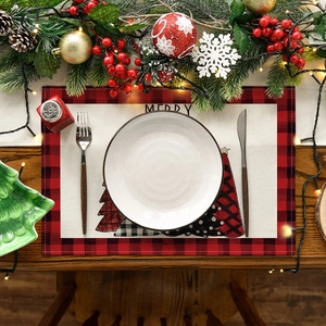 Close-up of buffalo plaid Christmas placemat with festive tree and Merry text on wood table