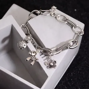 Vintage silver chain bracelet with fortune bag horse and flower charms on a stone pedestal