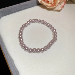 Macro shot of elegant lavender pearl beaded necklace on a soft fabric stand with pink floral accents