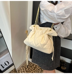 Detail of white quilted leather bucket bag with gold-tone chain strap and woven leather
