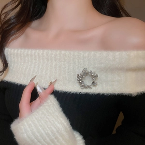 Close-up of a silver wreath brooch with pearls and zircons on a white knit sweater
