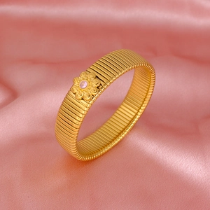 Detail of a gold plated flexible bangle with a pink stone floral charm on silk