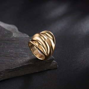 Gold vintage wide band ring with irregular wave texture displayed on black stone