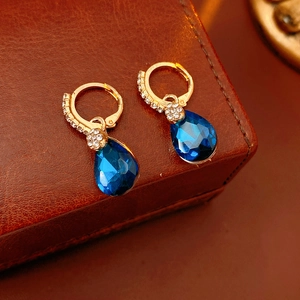 Vue détaillée de boucles d'oreilles dorées avec gouttes bleues et zircons brillants