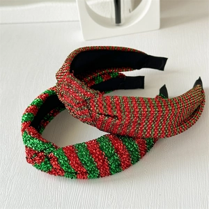 Close-up of red and green sequined striped knotted headbands on a white wooden surface
