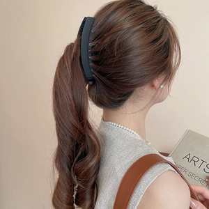 Vue détaillée d'une grande pince à cheveux noir mat tenant des cheveux longs et ondulés