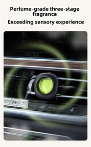 Detail of a black car air vent aroma clip with green liquid in a premium car interior