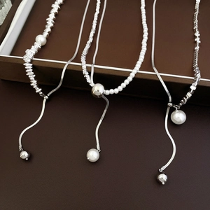 Detail of silver snake chain necklace featuring irregular metal beads and white pearls