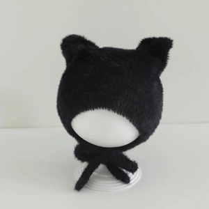 Close-up of black plush winter hat with cat ears and tie straps for infants