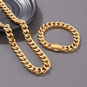 Close-up of gold 18K plated Cuban link necklace and bracelet set on a black plate