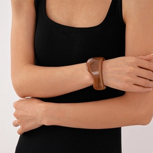 Close-up of a wide amber acrylic cuff bracelet with marble texture worn by a model