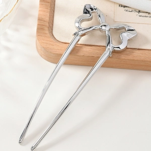 Elegant silver metal bow U-shaped hair pin for bun styling on a light wooden tray
