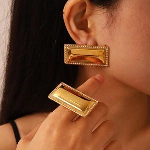 Detail of gold rectangular earrings and ring set with sparkling zircon border on model