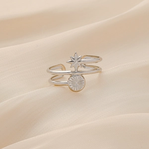 Détail macro du pendentif étoile et pièce sur bague ajustable en argent poli