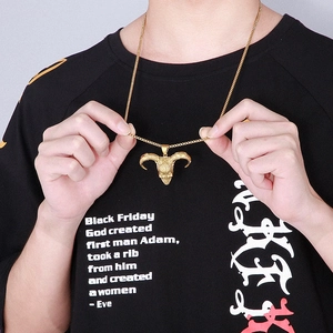Detailed view of men's gold ram skull pendant with box chain on male model wearing black tee