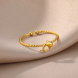 Macro detail of gold-plated twisted band ring featuring a polished dolphin centerpiece
