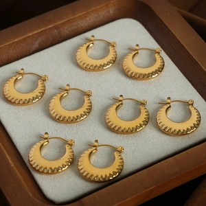 Vintage gold chunky hoop earrings with textured ripple design on wooden jewelry tray