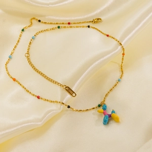 Close-up of gold stainless steel necklace with colorful balloon dog pendant on silk