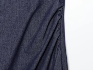 Detailed view of dark blue denim fabric with ruched design and visible twill texture