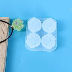 Macro shot of 4-cavity cat paw silicone mold with green resin craft on blue background