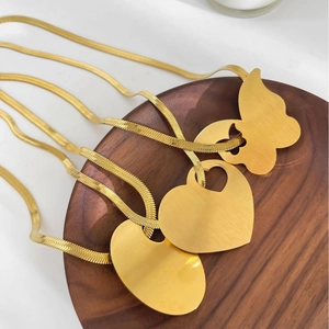 Vintage gold snake chain necklaces with butterfly and heart pendants on wood tray