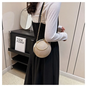 Close-up of golden sphere evening bag with woven texture, metal ring handle and chain strap