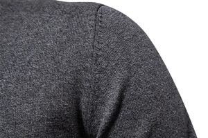 Macro shot of dark grey knit sweater showing reinforced shoulder seams and premium fabric