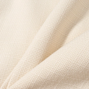 Primo piano del tessuto intrecciato beige che mostra la trama dettagliata della giacca