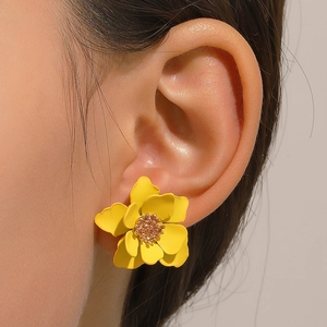 Close-up of a model wearing yellow matte layered flower earrings with golden centers