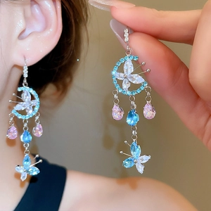 Close-up of tassel earrings with moon, butterfly elements and blue crystal rhinestones