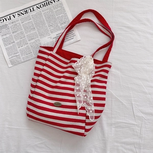 Detail of red and white striped canvas tote bag with lace scarf and brand emblem