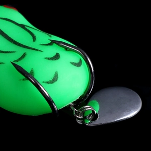Close-up of a green frog lure with black patterns, sharp metal hooks and a spinning blade