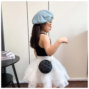 Close-up of kids black quilted round crossbody bag with golden chain and denim beret