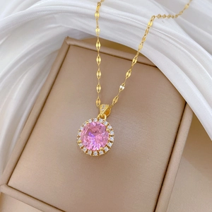 Close-up of gold-plated necklace with pink round gemstone and pavé crystal accents