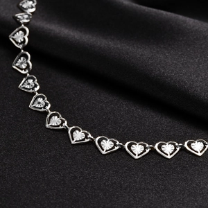 Macro shot of silver hollow heart chain links with radial texture on black silk fabric