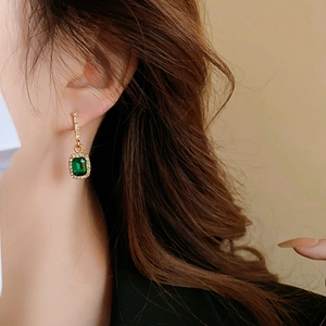 Nahaufnahme von luxuriösen smaragdgrünen Ohrhängern mit Diamanten und Gold-Finish