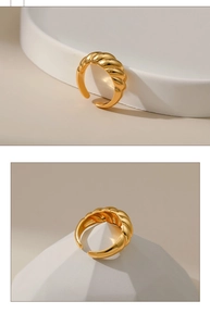 Detailed view of a gold-plated twisted croissant ring on a geometric minimalist display