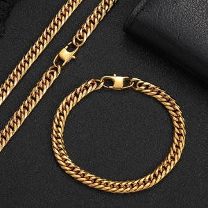 Detail of gold Cuban link chain necklace and bracelet set with lobster clasp on black background