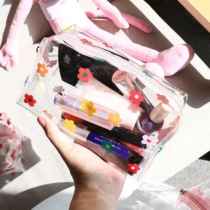 Macro detail of clear PVC makeup bag featuring colorful floral prints and portable size