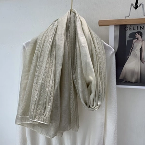 Detail of beige linen cotton scarf featuring elegant vertical lace patchwork design