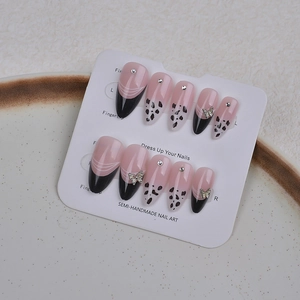 Detailansicht der rosa Press-on-Nägel mit schwarzen French Tips und Gold-Schmetterlingen
