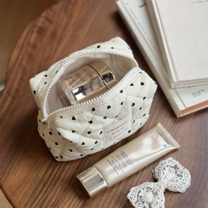 Detailed view of cream quilted cotton pouch with heart print on a wooden desk
