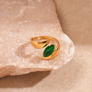Detail of adjustable gold ring with marquise-cut green zircon on a brown stone base