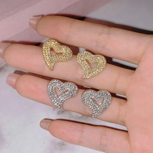 Gold and silver heart stud earrings with sparkling cubic zirconia on a marble background